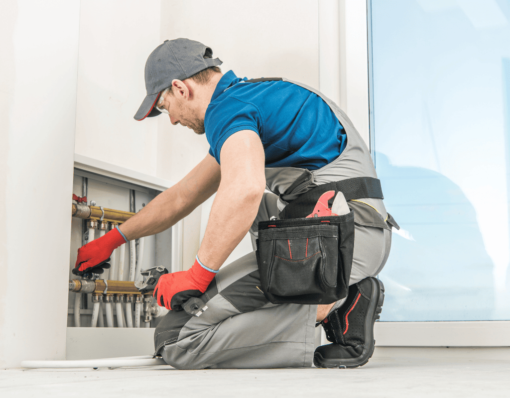 plumber repairing pipe connections inside residential property