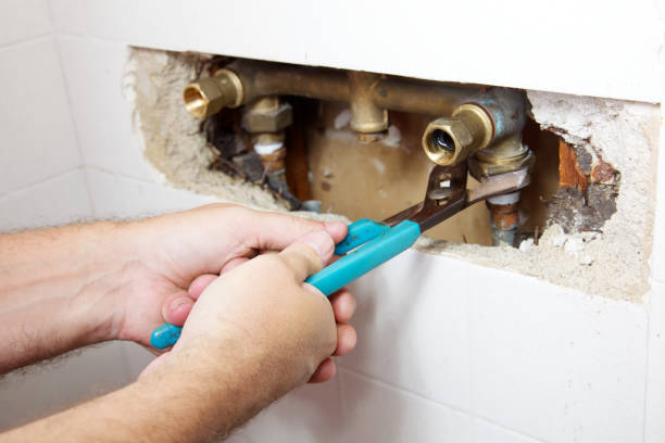 Experienced plumber inspecting corroded fittings and testing water pressure professionally