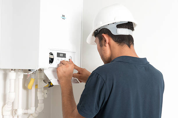 Technician repairing leaking residential water heater in San Luis Obispo garage during morning service call