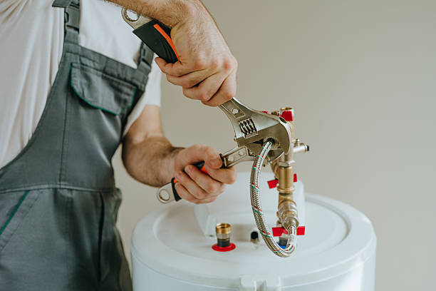 Plumber testing water heater components with diagnostic tools beside residential utility closet